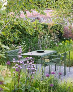 a table and chairs in the middle of a garden