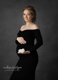 a pregnant woman in a black dress holding a piece of cake