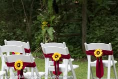 white folding chairs with red sashes and sunflowers tied to the seats are ready for an outdoor ceremony