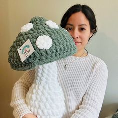 a woman holding up a crocheted stuffed animal