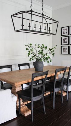 a dining room table with black chairs and a potted plant on top of it