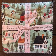 a wrapping paper wrapped in pink ribbon on top of a wooden surface with houses and trees