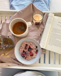 an open book and bowl of oatmeal next to a cup of tea