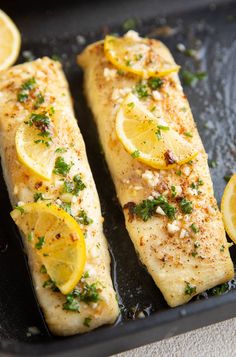 two fish fillets with lemon slices and parsley