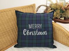 a christmas pillow sitting on top of a wicker chair next to a potted plant