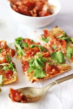 slices of pizza with tomatoes, lettuce and other toppings next to a bowl of salad