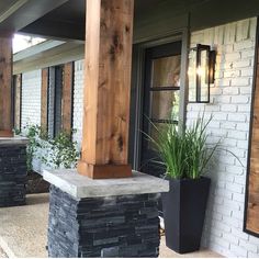 an outside view of a building with some plants on the front porch and two large black planters