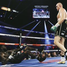 a man standing next to a referee in a boxing ring