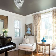 a living room filled with furniture and a chandelier hanging from the ceiling over a piano