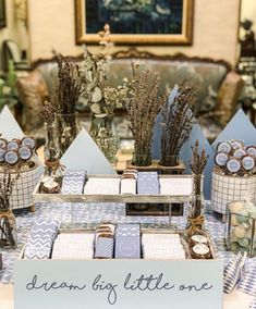 a table topped with lots of blue and white desserts next to a sign that says, dream big little one