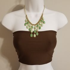 a mannequin with a brown top and green necklace