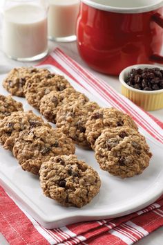 cookies and raisins on a white plate next to milk