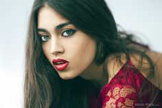 a woman with long dark hair and red lipstick on her face, posing for the camera