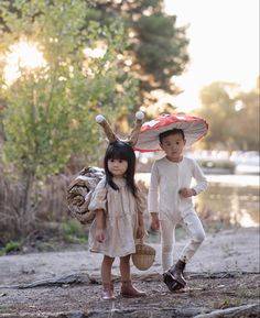 two young children are dressed up in costumes and holding umbrellas while standing on the ground