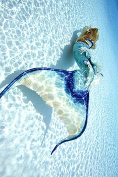 a woman in a blue and white dress is swimming with a fish on her back