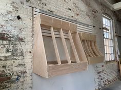 a row of wooden shelves on the side of a brick wall next to a window