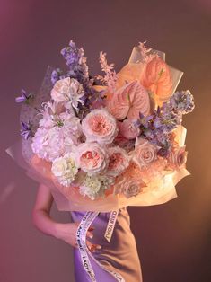 a woman holding a bouquet of flowers in front of her face and wearing a purple dress