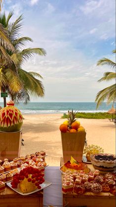 there are many desserts on the table at this beachside party, including oranges and pineapples