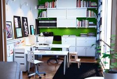 an office with white desks and green bookshelves