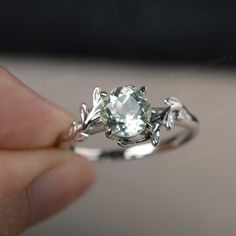 a person is holding a ring with an aqua blue stone in it's center