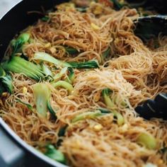 noodles and vegetables being cooked in a pan