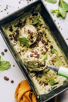 an ice cream dish with mint leaves and chocolate chips on the side, in a metal pan