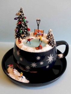 a tea cup decorated with christmas trees and snowflakes is shown on a black saucer