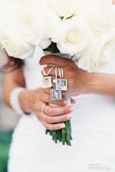 a bride holding a bouquet of white roses and two wedding rings on her finger,