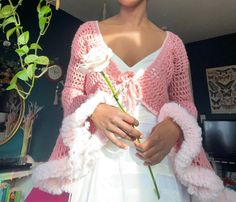 a mannequin holding a rose in her hands and wearing a pink cardigan