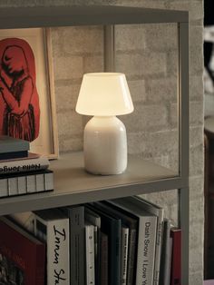 a white lamp sitting on top of a book shelf