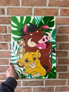 the lion king and other disney characters are depicted on a canvas mounted on a brick wall