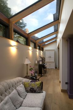 a living room filled with furniture under a skylight next to a wall mounted flat screen tv