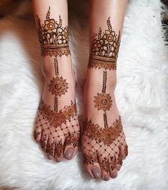 a woman's feet with hennap and flowers on them, sitting on a fluffy white rug