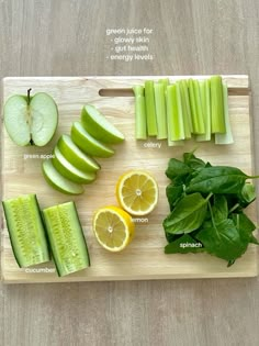 a cutting board topped with sliced up green apples and cucumbers next to lemon slices