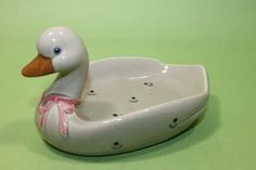 a white ceramic ducky with pink ribbon on it's head