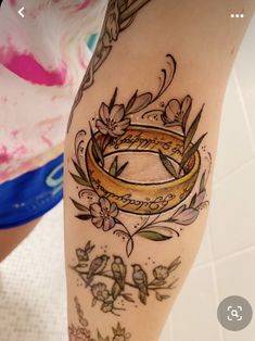 a woman's leg with a tattoo on it that has a gold ring in the middle