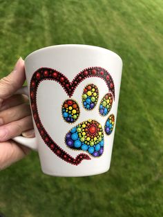 a hand holding a coffee cup with a dog's paw painted on the side