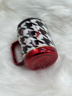 a red and black can sitting on top of a white fur covered floor