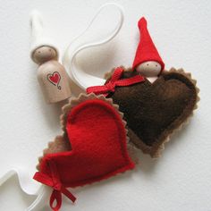 two felt heart ornaments are sitting next to each other on a white surface, one is red and the other is brown