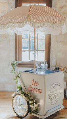 a small ice cream cart with an umbrella over it