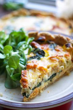 a slice of quiche with spinach and greens on a plate