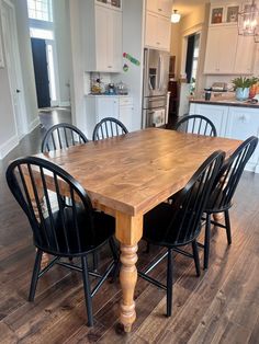 a wooden table surrounded by black chairs in a kitchen