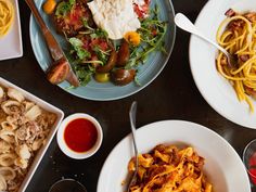 a table topped with plates of food and pasta