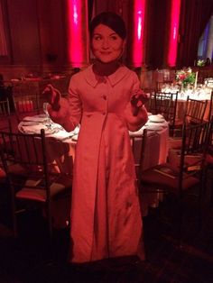 a woman standing in front of a table with chairs