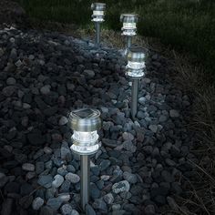 three lights that are on some rocks in the grass and one light is turned on