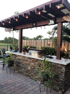 an outdoor bar with lights and potted plants on the outside wall next to it