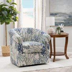 a blue and white chair sitting in front of a window next to a table with a potted plant on it