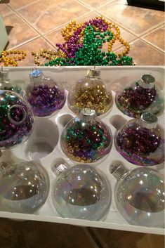 a person is holding a tray filled with christmas ornament ornaments and beads on the table