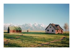 an old farm with two barns and mountains in the background