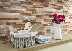 a kitchen counter with utensils and flowers in a basket next to a brick wall